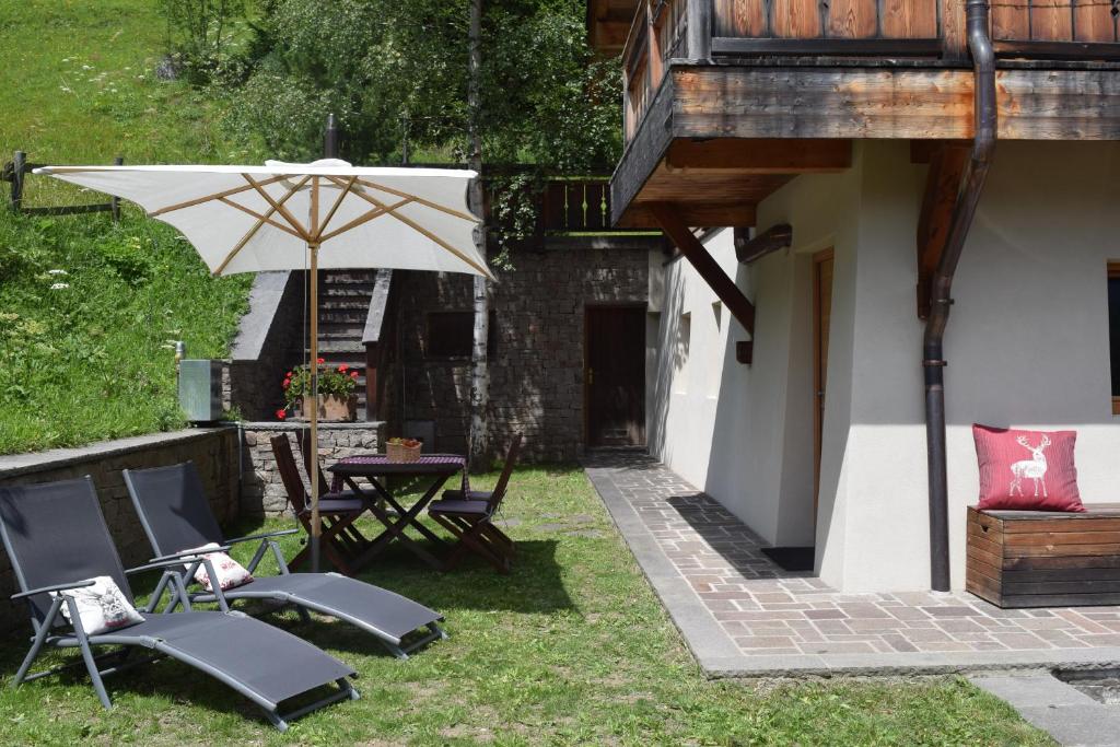 博萨迪法萨Chalet Do Costa的庭院配有桌椅和遮阳伞。