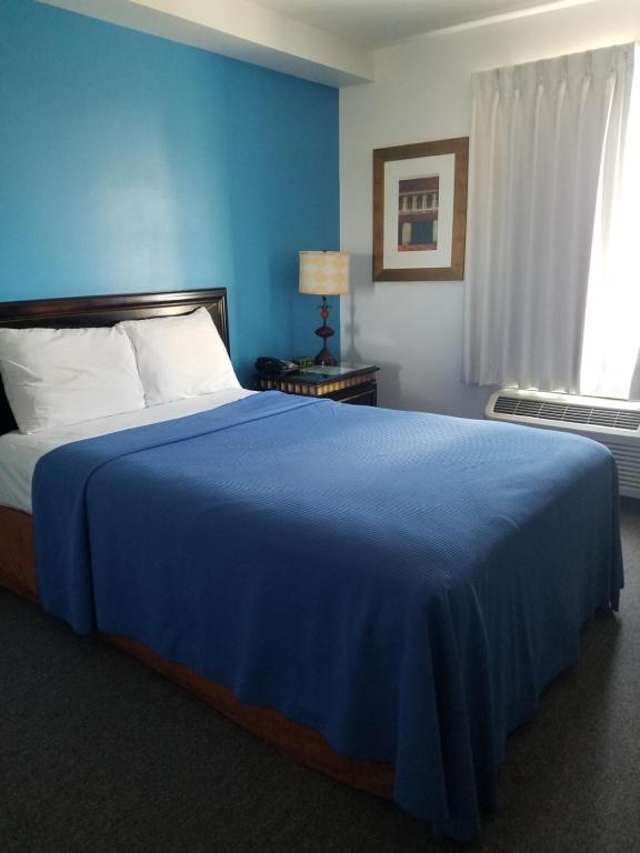 威利斯顿Ramada by Wyndham Williston的蓝色卧室配有一张带蓝色毯子的大床