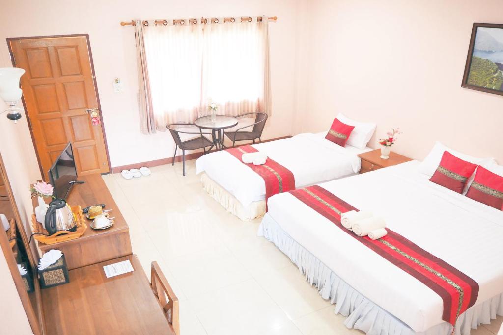 Ban Lai Ngao康柯丽德度假酒店的酒店客房设有两张床和一张桌子。