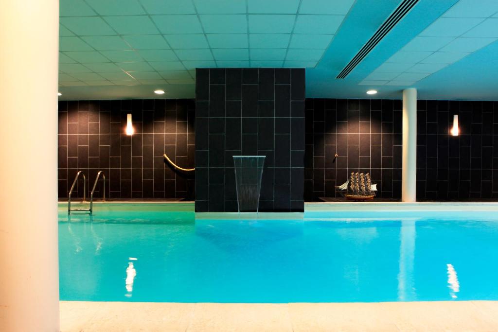 巴黎Amiral Hôtel的蓝色的海水和黑色瓷砖游泳池
