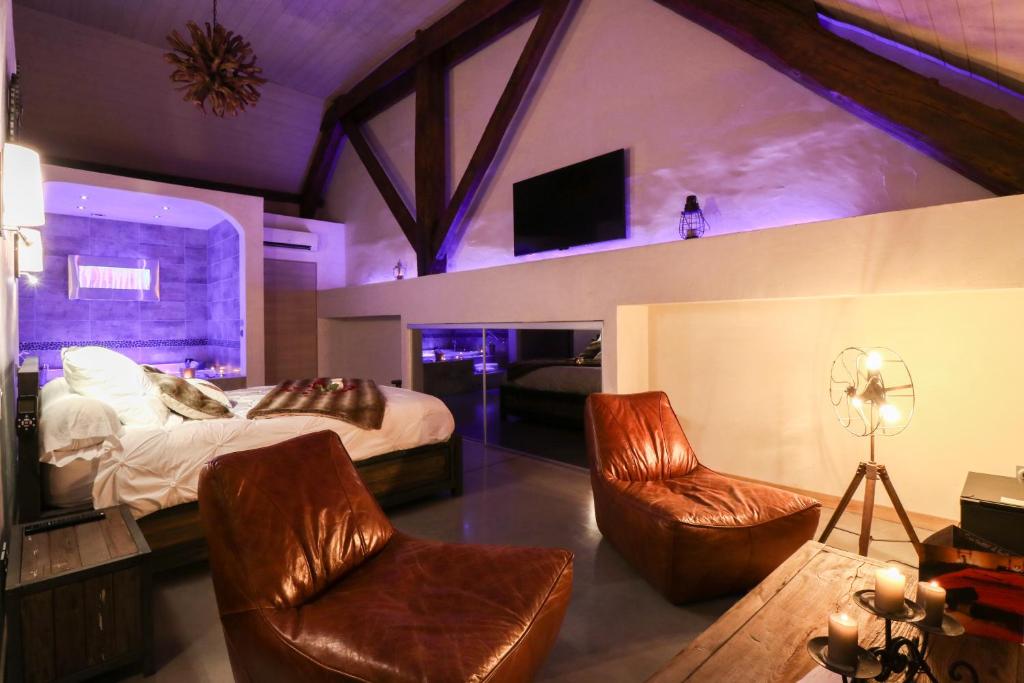 圣吉尔Abri Cosy - Suite Romantique的一间卧室配有一张床、两把椅子和一台电视