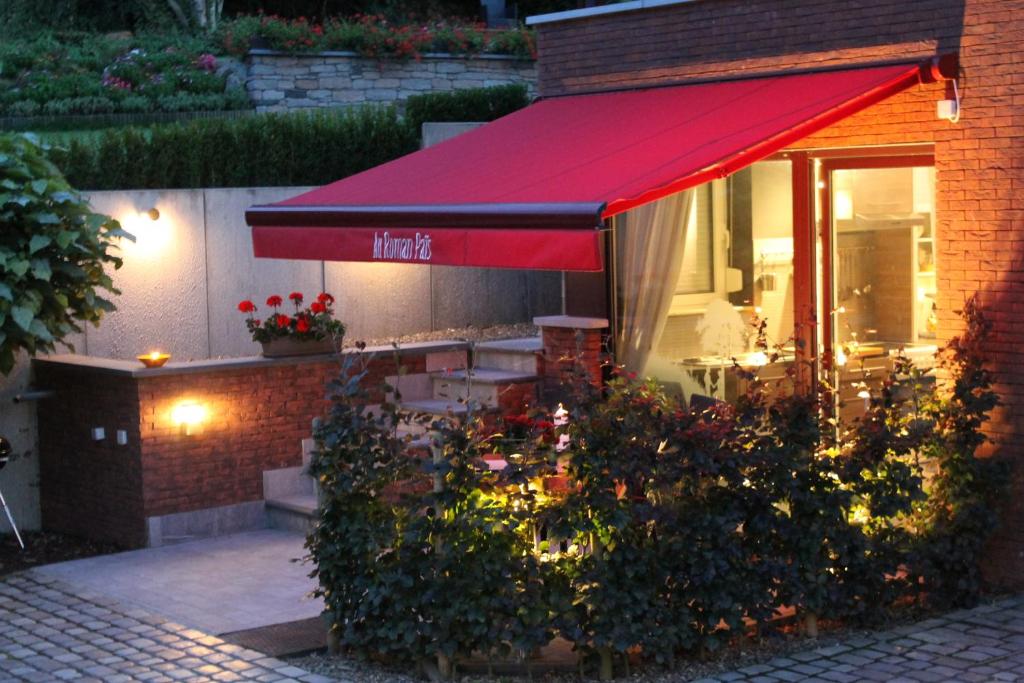 布赖恩勒沙托罗曼派斯住宿加早餐旅馆的一间有红色遮阳篷和一些鲜花的餐厅