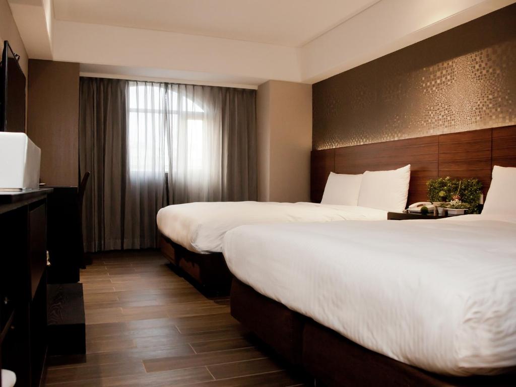台北凯统饭店的酒店客房设有两张床和窗户。