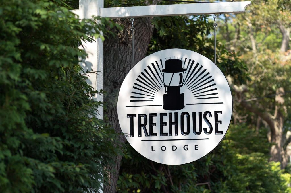 伍兹霍尔Treehouse Lodge的挂在树上的树屋小屋的标志