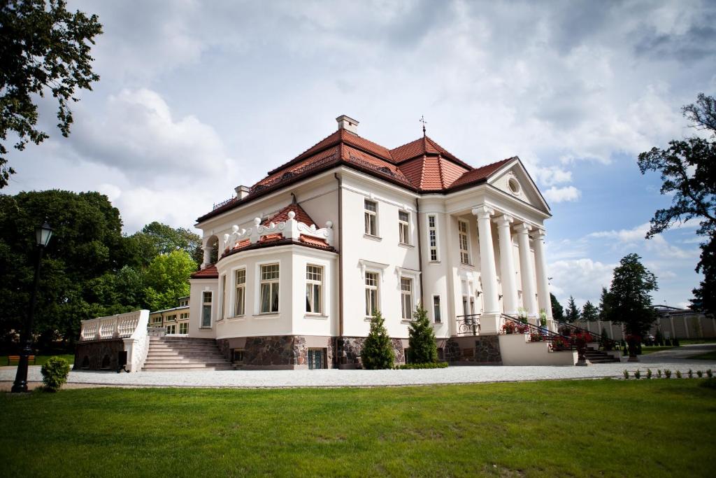 卡利什Pałac Tłokinia的一座大型白色房屋,设有红色屋顶