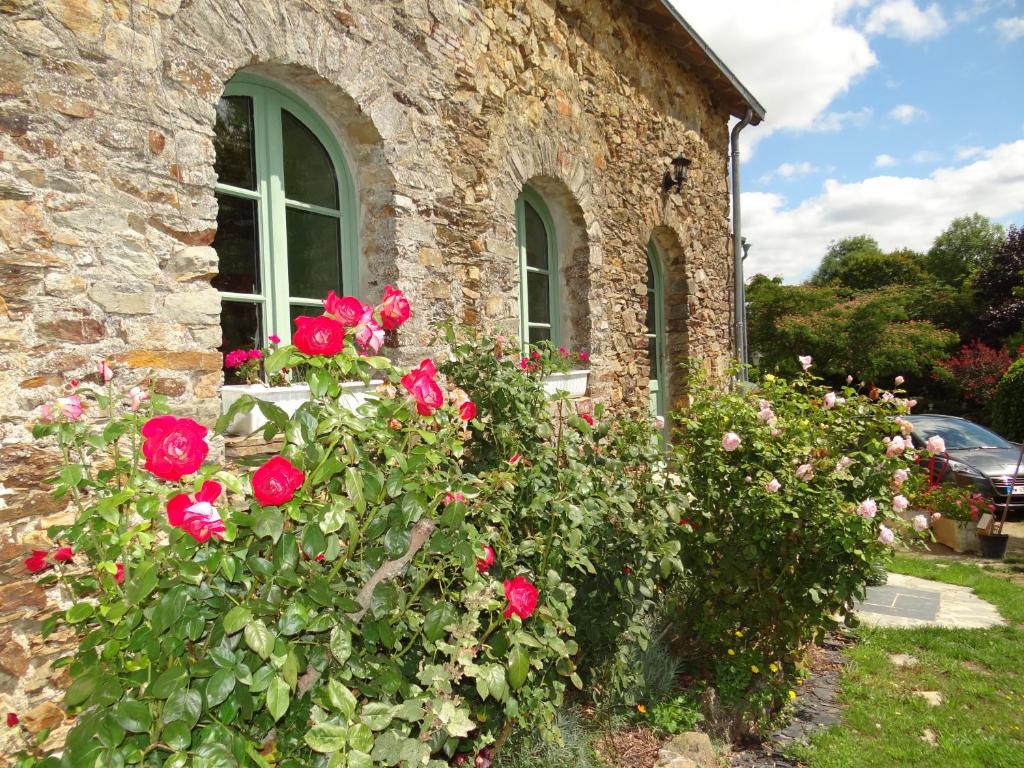 AhuilléLogis de la Provosterie的窗户前有玫瑰的石头房子