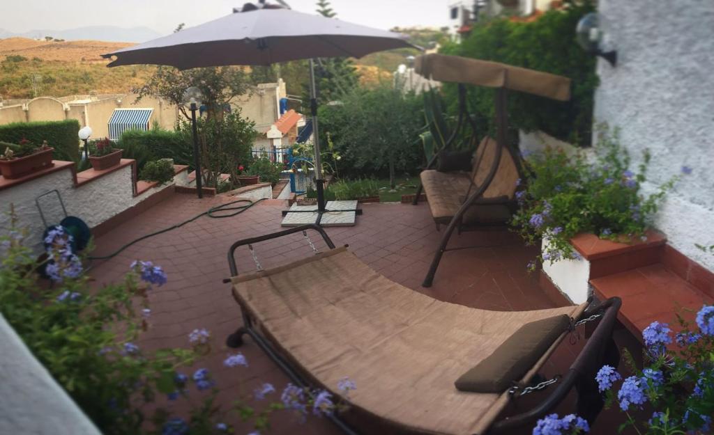 圣尼科拉阿尔切拉Villetta Clorinda的庭院设有木凳和遮阳伞。