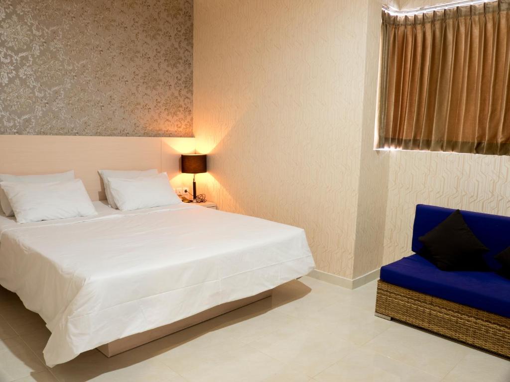 泗水SWK95号酒店的卧室配有白色的床和蓝色椅子