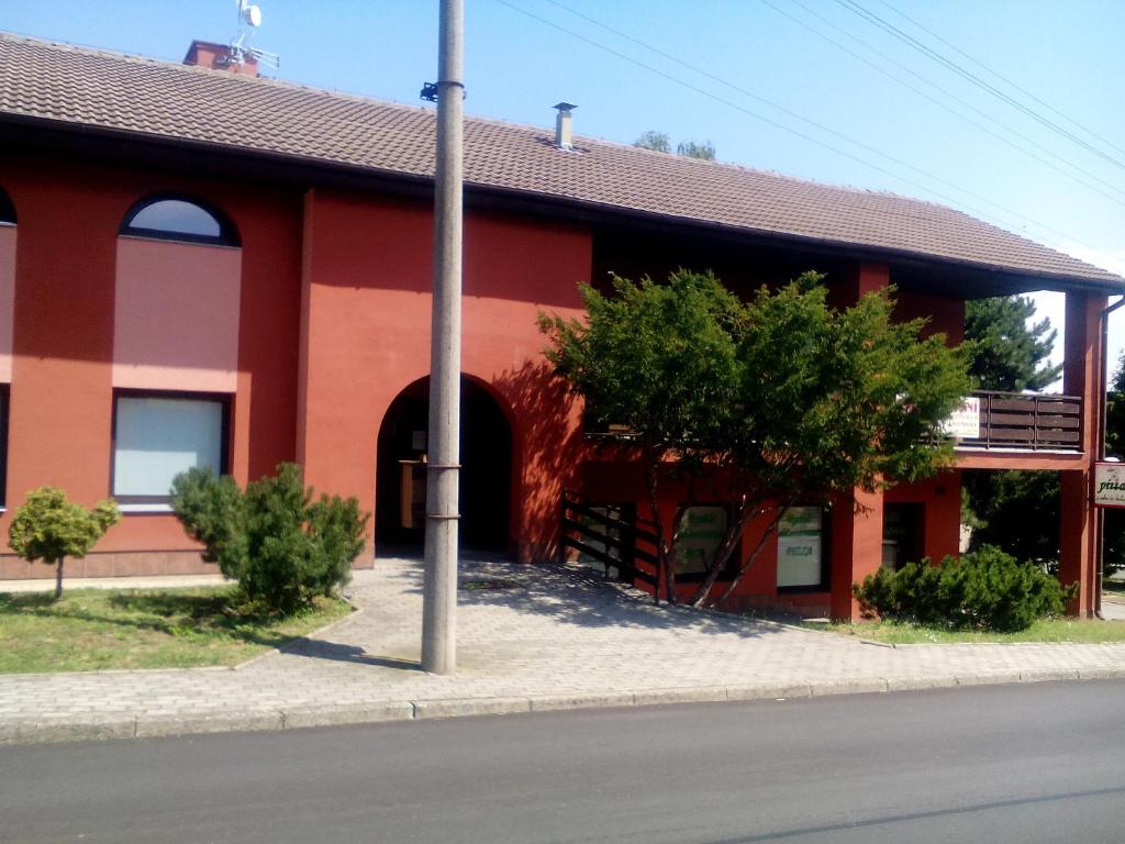 VacenoviceOaza的前面有棵树的红色建筑