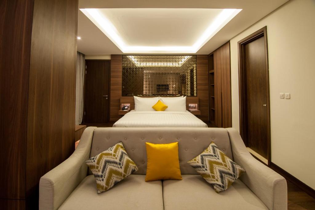 当格浪格兰德索尔海滨酒店的一间卧室配有一张床和一张带黄色枕头的沙发。