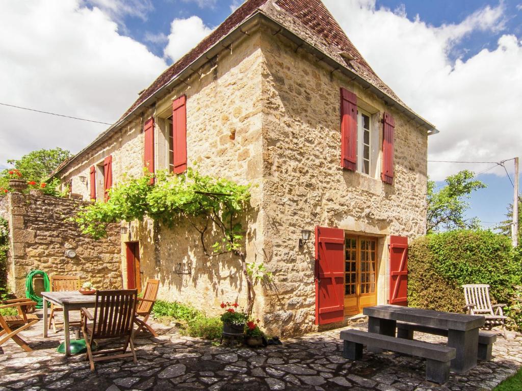 Saint-CybranetFarmhouse in Saint Cybranet with Private Garden的一座古老的石头房子,配有红色百叶窗和野餐桌