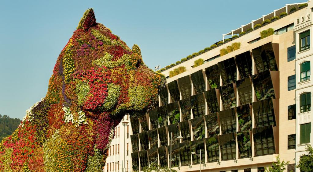 毕尔巴鄂The Artist Grand Hotel of Art的建筑前花朵覆盖的狗雕塑