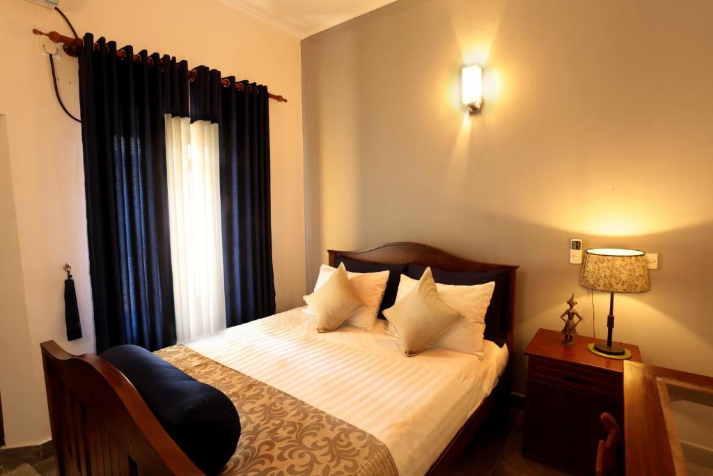 努格古达米特拉宇酒店的一间卧室配有一张带白色床单的床和一扇窗户。