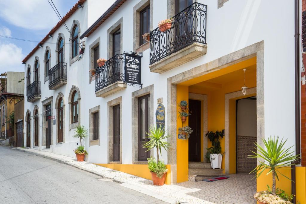 Caldas de São JorgeCasa do Campo AL的一条有白色和黄色建筑的街道,种植了盆栽植物