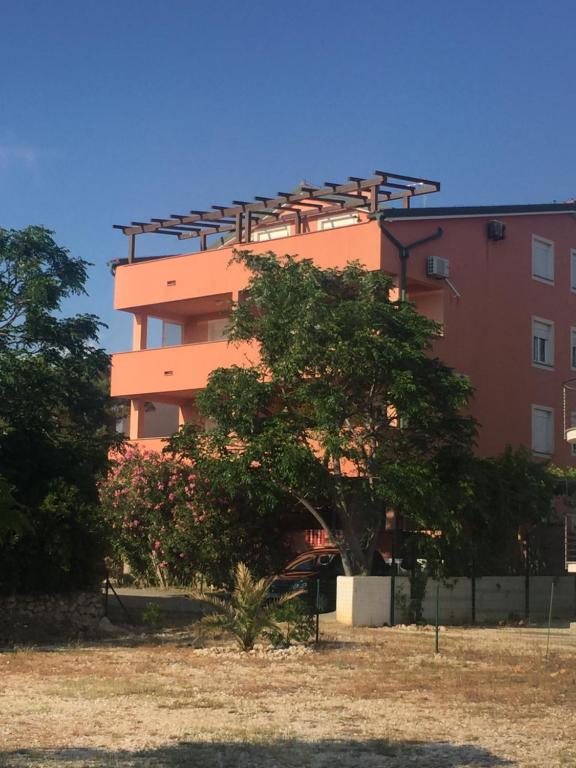 波弗加纳Apartments Vidovic的一座橘色的建筑,前面有一棵树