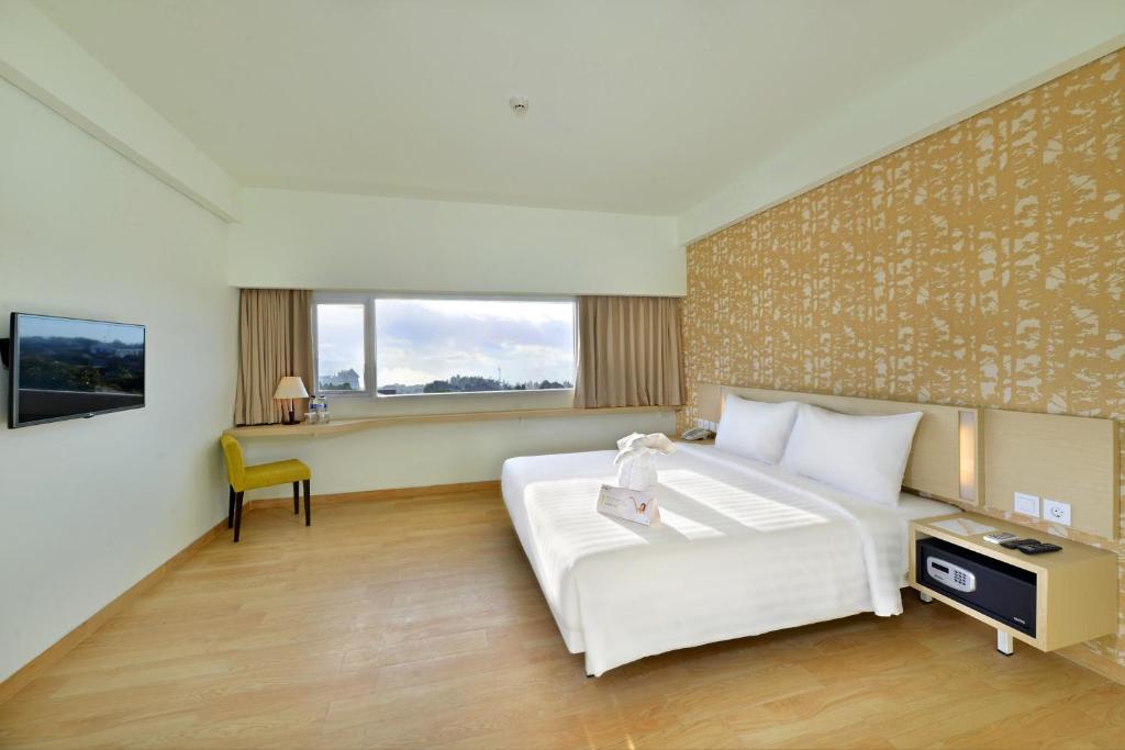 芝拉扎Whiz Prime Hotel Sudirman Cilacap的卧室配有一张白色大床和一张书桌