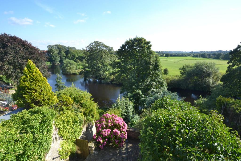 韦瑟比Riverside Cottage的享有花园的空中美景,花园内种有鲜花,河流