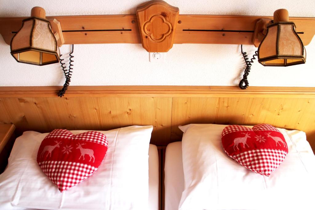 格林德尔瓦尔德阿尔彭霍夫酒店的床上的2个红色和白色枕头,配有2盏灯