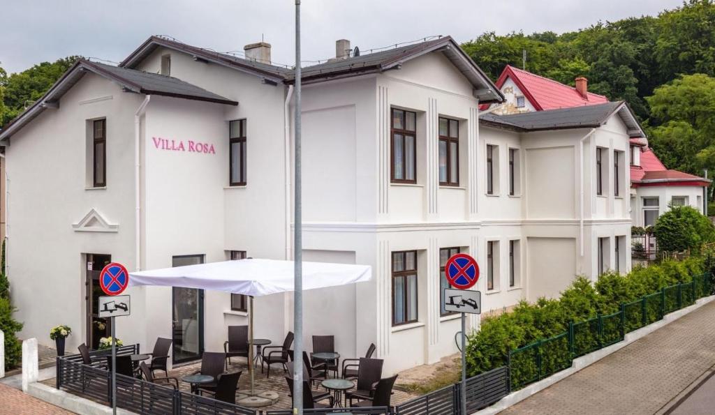 米兹多洛杰Villa Rosa - 200m od morza的一座白色的建筑,前面设有椅子和遮阳伞