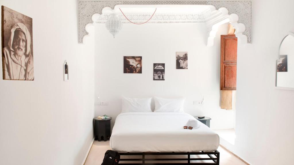 马拉喀什The Central House Marrakech Medina的卧室配有白色的床,墙上挂有图片