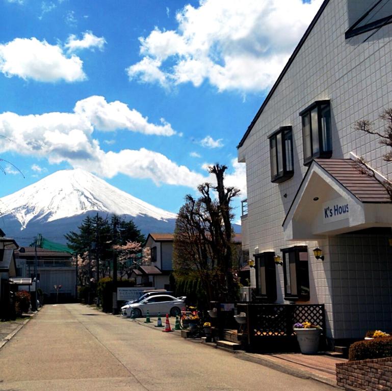 富士河口湖K's House Fuji View - Travelers Hostel的一座建筑物后面的雪覆盖的山