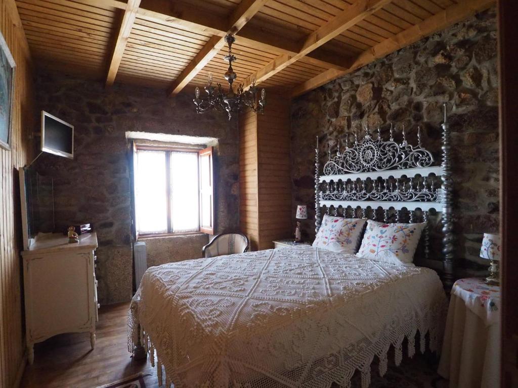 LeomilCasa do Monge的卧室配有一张石墙内的大床