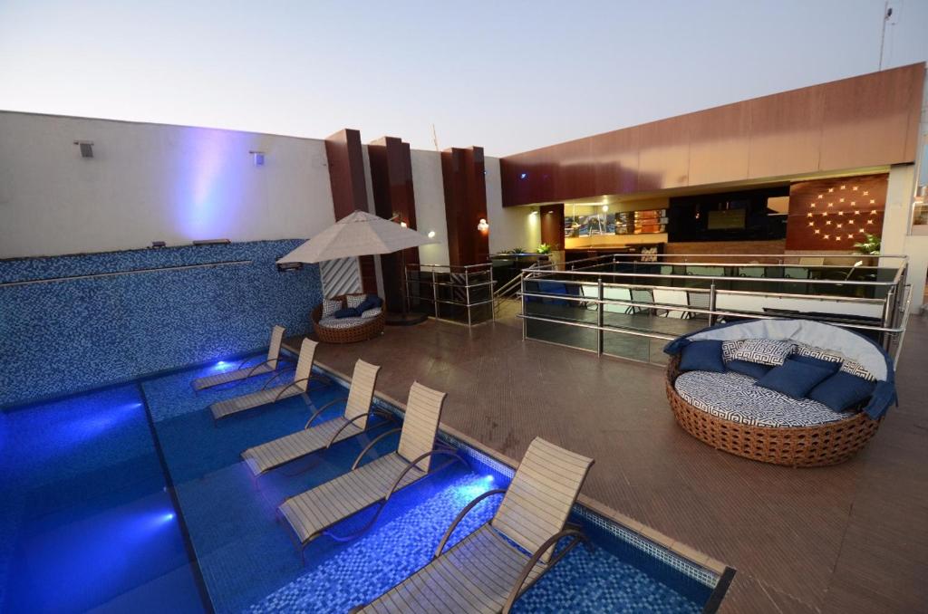波多韦柳奥斯卡行政酒店的客房设有带椅子和沙发的游泳池。