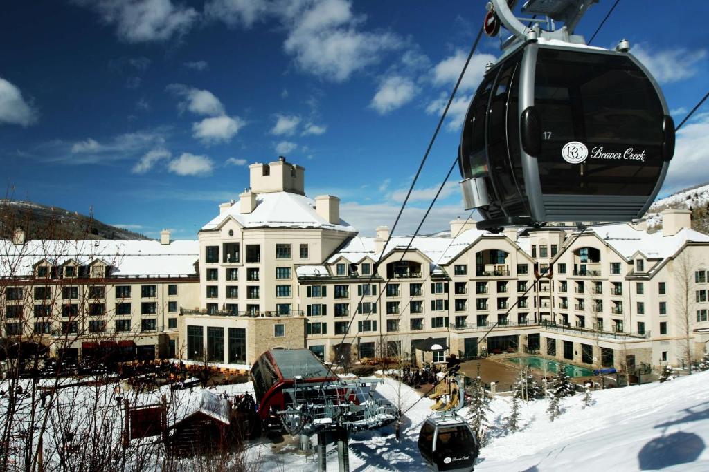 比弗河Park Hyatt Beaver Creek Resort and Spa, Vail Valley的雪地里一座大建筑上方的空中缆车