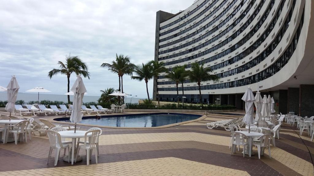 萨尔瓦多Apart Hotel em Ondina的一座配有白色桌椅的游泳池