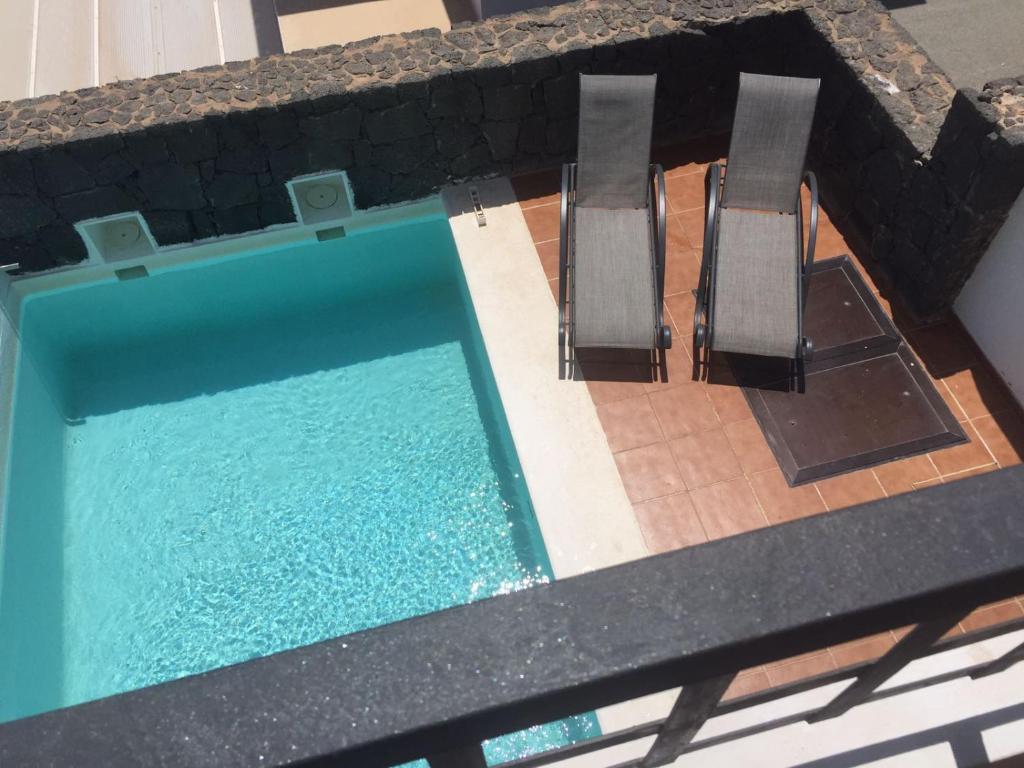 普拉亚布兰卡Villa Rubicon Playa的游泳池旁设有两把椅子
