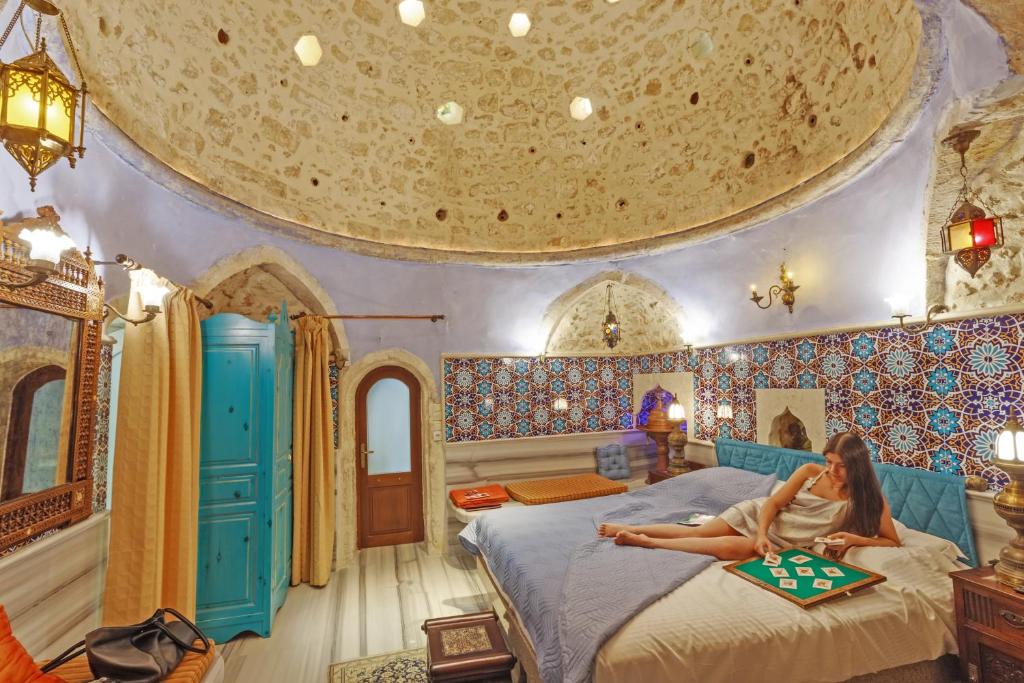 罗希姆诺Hamam Oriental Suites的坐在天花板房间的床上的女人
