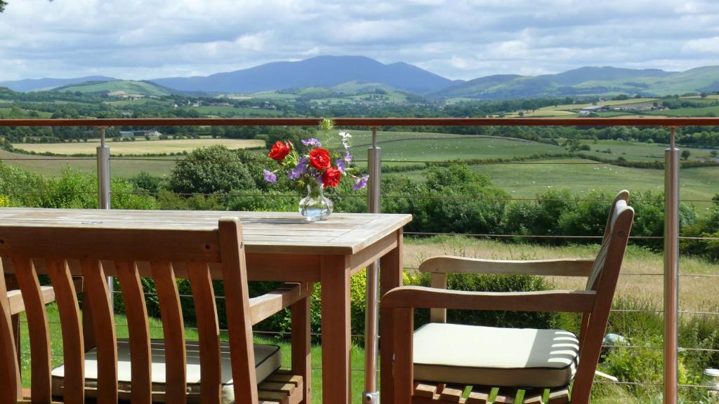 科克茅斯Westwood - The B&B with a view的阳台上的桌椅和花瓶