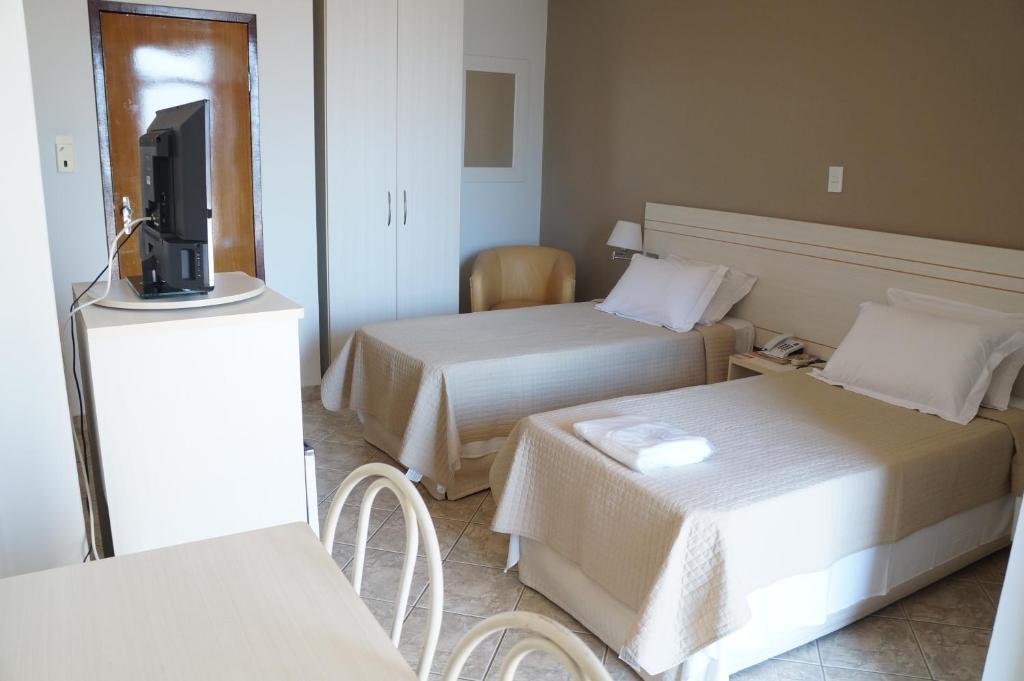 马纽阿苏Manhuaçu Center Hotel的酒店客房设有两张床和一台平面电视。