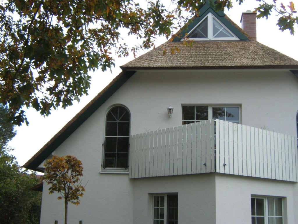 青斯特Zingst-3-Zi-Ferienwohnung-DEICHIDYLL-Strandresidenz-Godeke-Michels的白色的房子,有陡峭的屋顶和窗户