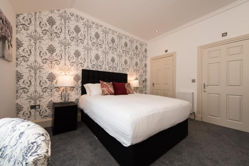 爱丁堡皇家王子套房公寓的卧室配有一张白色大床和壁纸