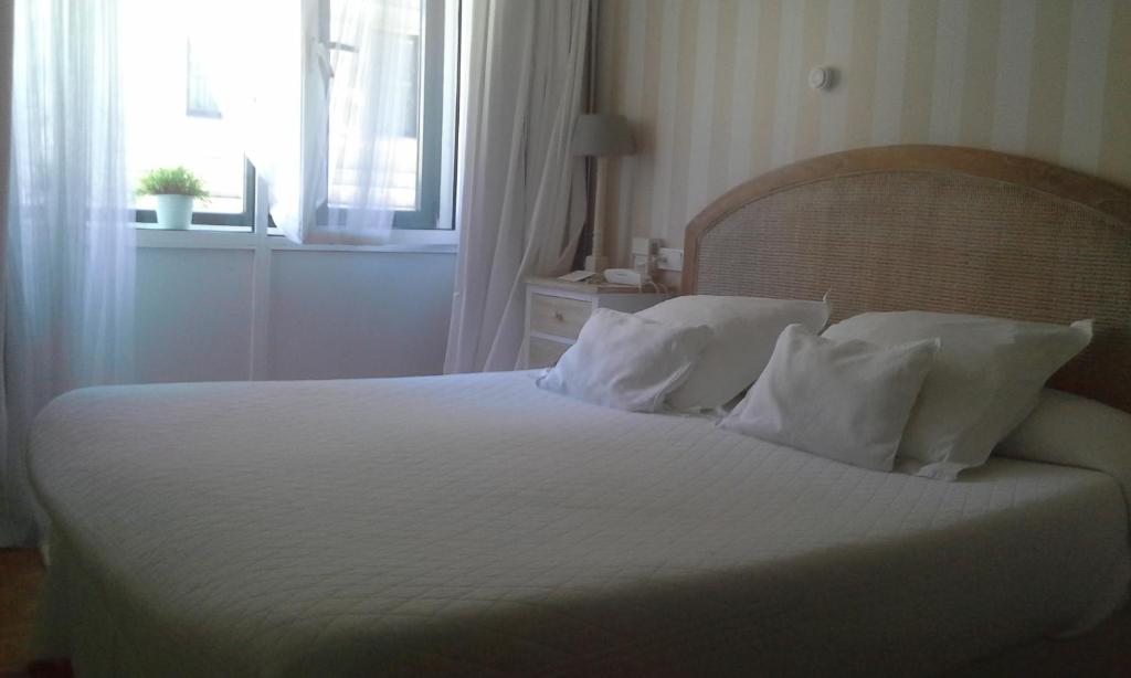 希洪中央酒店的卧室配有带枕头的白色床和窗户。