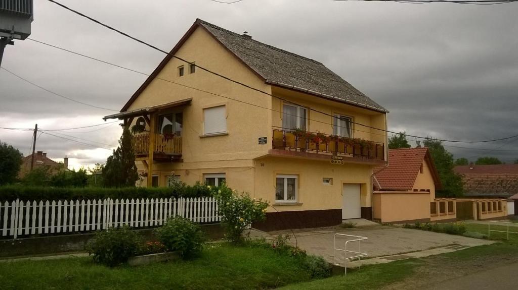 VerpelétKeletifény Vendégház的前面有白色围栏的黄色房子