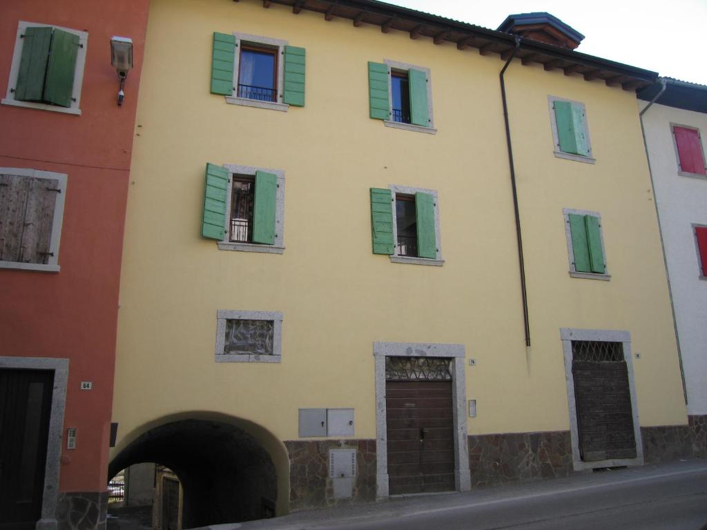 Tiarno di SottoCasa Anita的黄色建筑,上面有绿色百叶窗