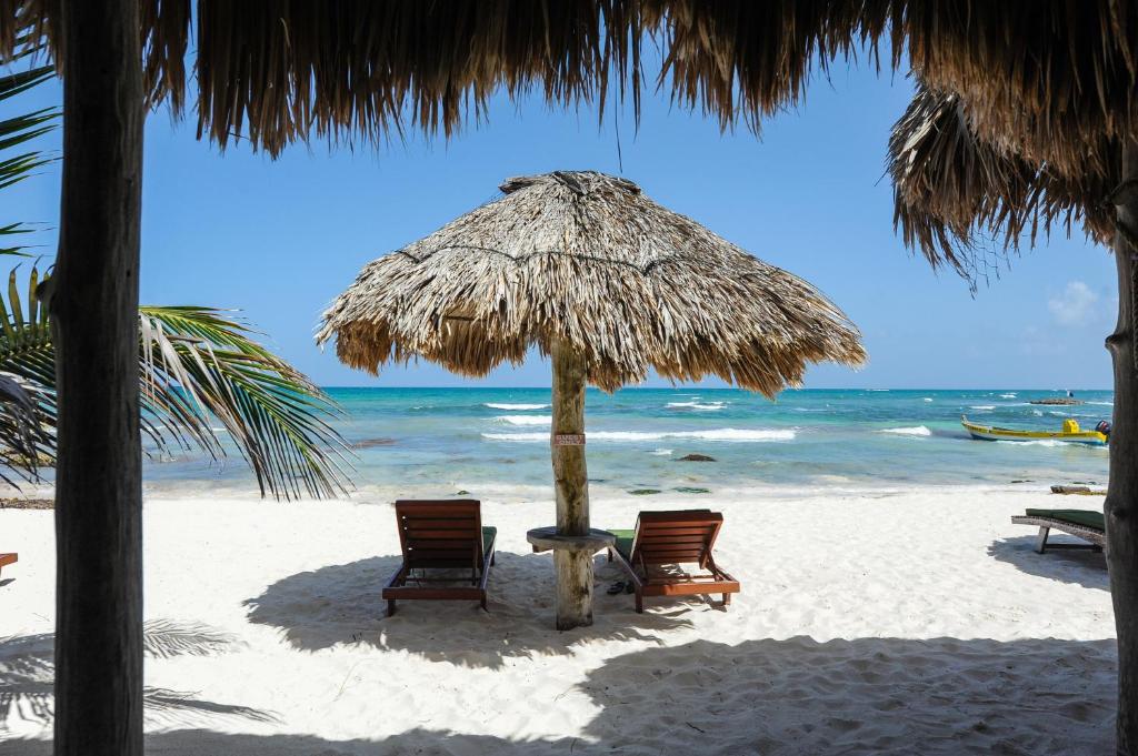 图卢姆萨玛斯酒店的海滩上的两把椅子和一把遮阳伞