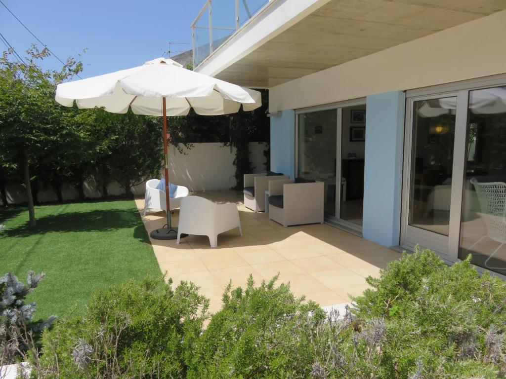 沙尔内卡Casa azul的一个带遮阳伞和白色椅子的庭院