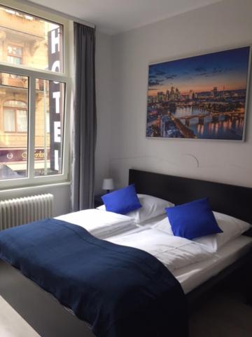 美因河畔法兰克福Main Hotel Frankfurt City的一间卧室配有两张带蓝色枕头的床和窗户。
