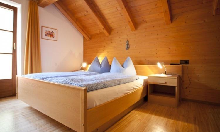 布列瑟农Huberhof的木制客房内的一间卧室,配有一张床