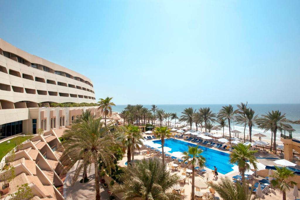 沙迦Occidental Sharjah Grand的享有棕榈树和游泳池度假村的空中景致