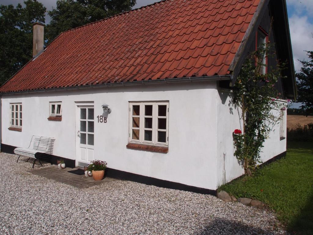 Funder KirkebyBjældskovgaard Holiday House的一间白色的小房子,有红色的屋顶
