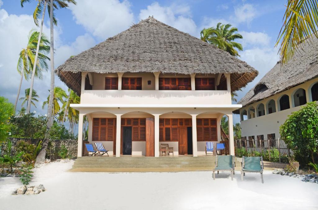 江比阿Alibi's Well的海滩上的房子,配有椅子和棕榈树