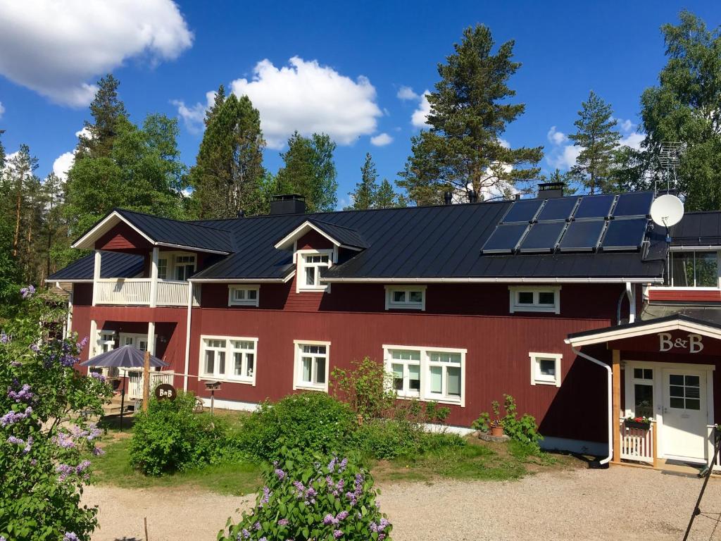 萨里耶尔维Purola Farm Guesthouse的屋顶上设有太阳能电池板的红色房子