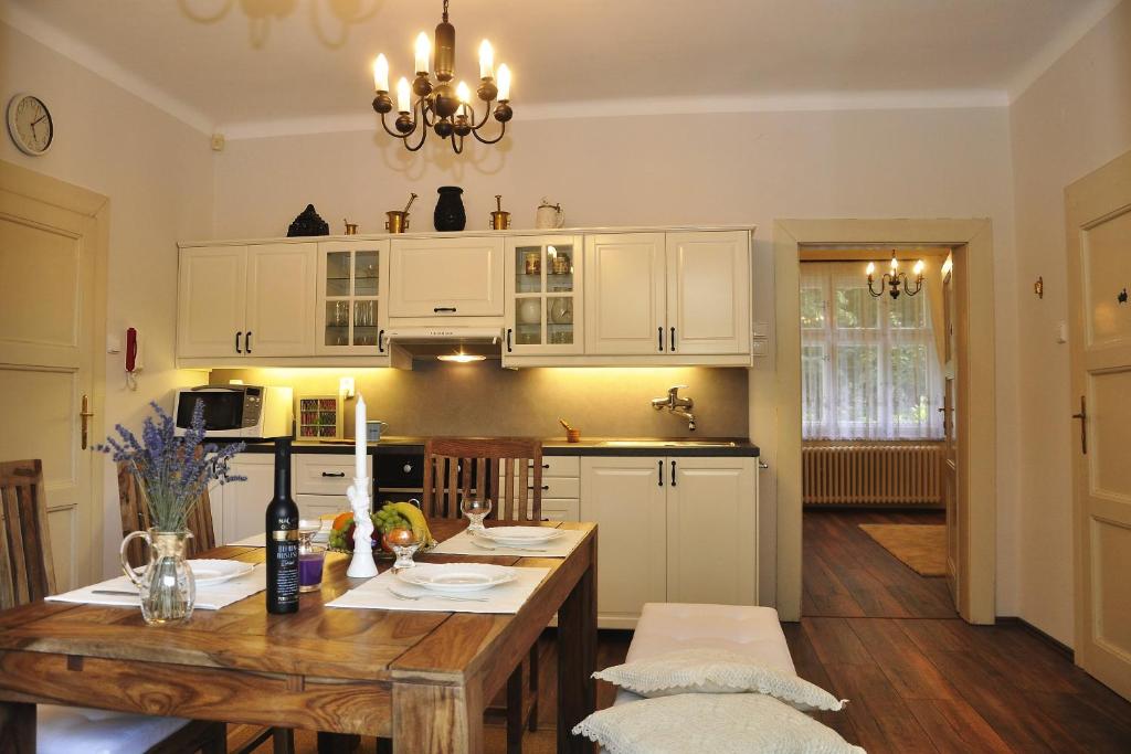 布拉格宁静大气公寓的厨房配有木桌和白色橱柜。