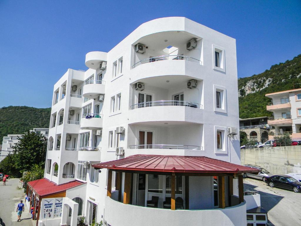 安吉Hotel Galeb的一座高大的白色建筑,有红色遮阳篷