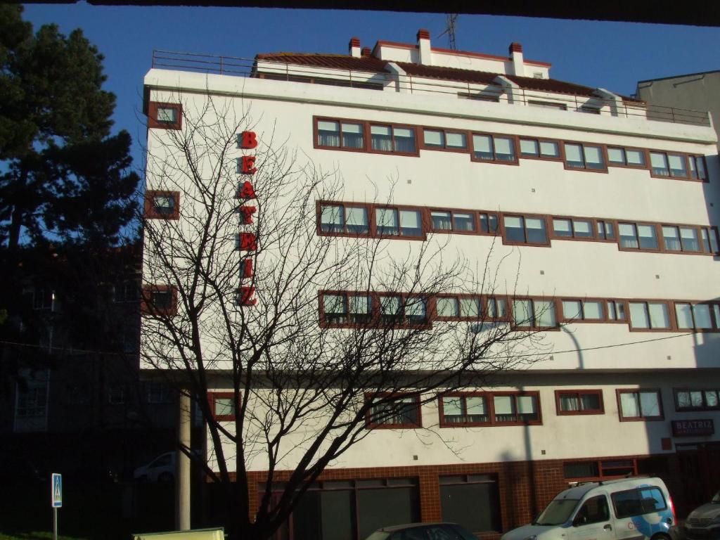 佩里洛Apartamentos Turisticos Beatriz的上面有红色标志的高大的白色建筑