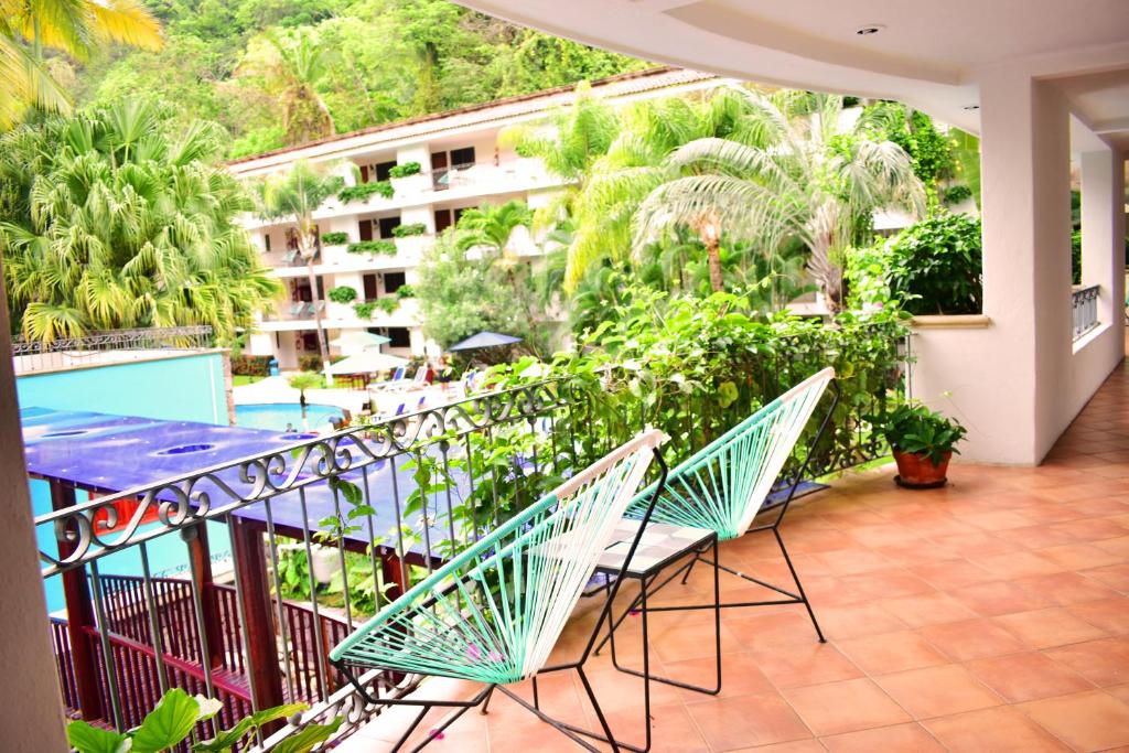 巴亚尔塔港Hotel Casa Iguana Mismaloya的一个带桌椅的阳台和一座建筑